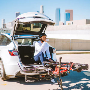 E-bikes loaded on a hitch rack behind an SUV in the city