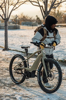 Rider with a fat-tire e-bike in fresh snow at sunrise