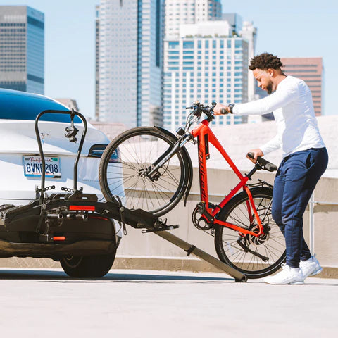 Rider loading an e-bike onto a hitch rack using the ramp